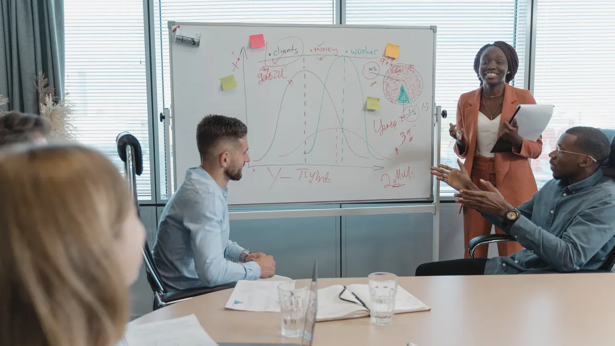 Team discussing sketches and sticky notes on a whiteboard