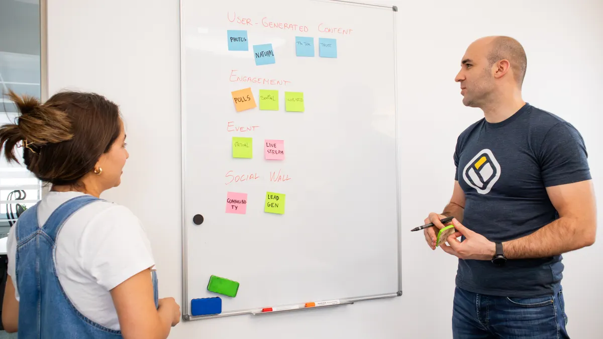 Two people reviewing a whiteboard covered in sticky notes